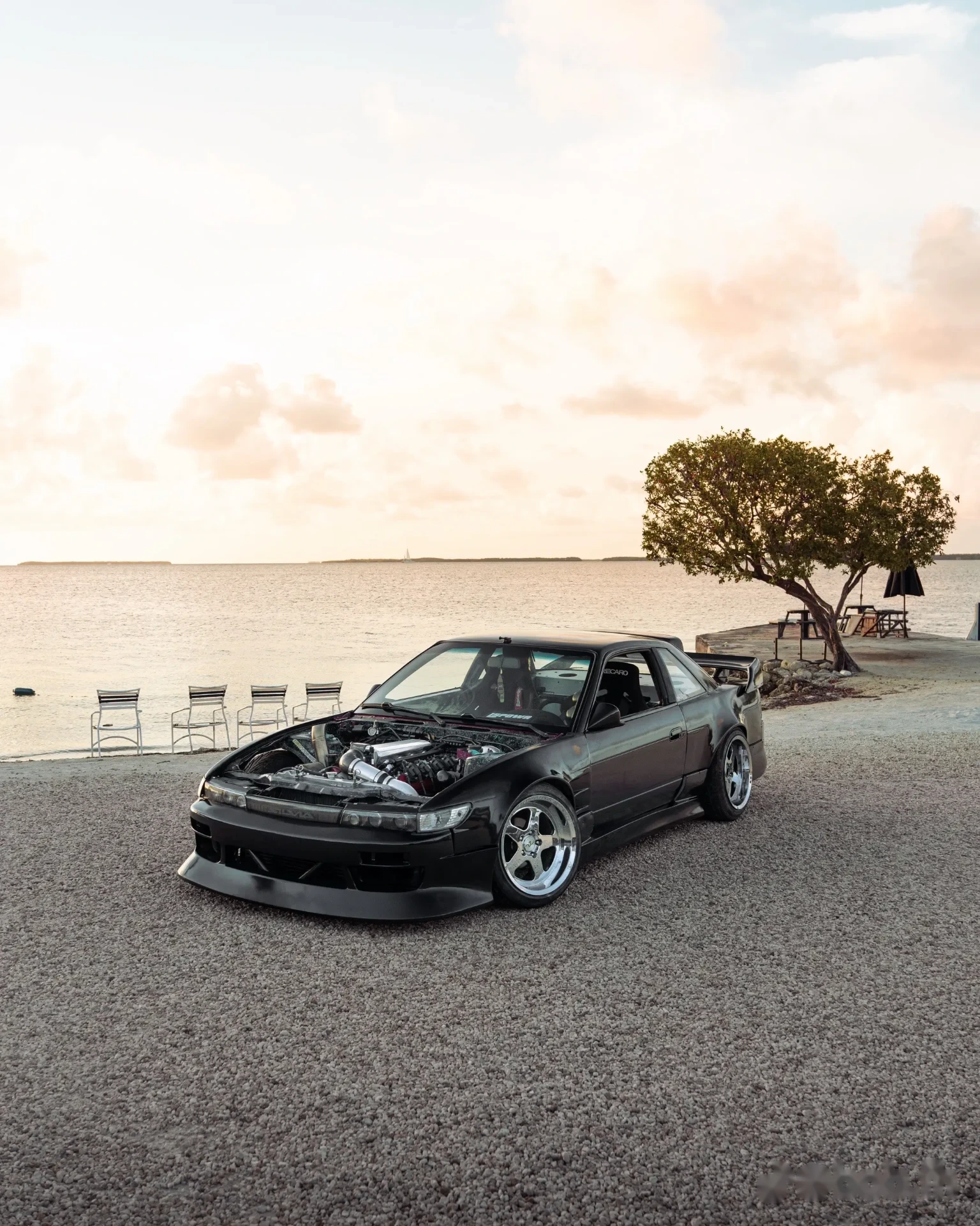 Black Nissan Silvia S13 by the ocean at sunset