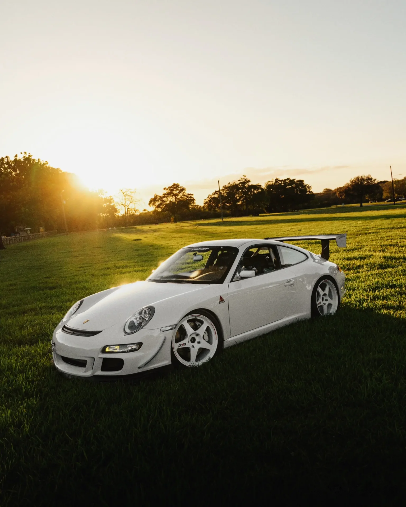 White Porsche 911 in a field at golden hour