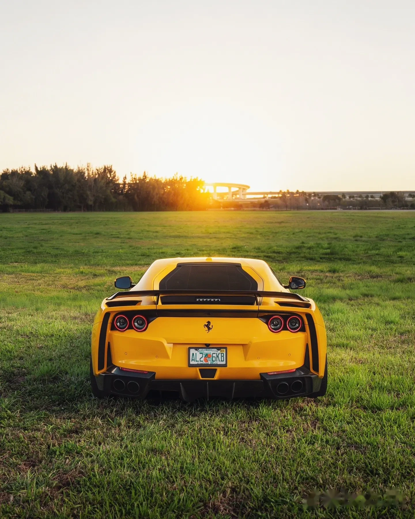 Yellow Ferrari 812 rear in an open field
