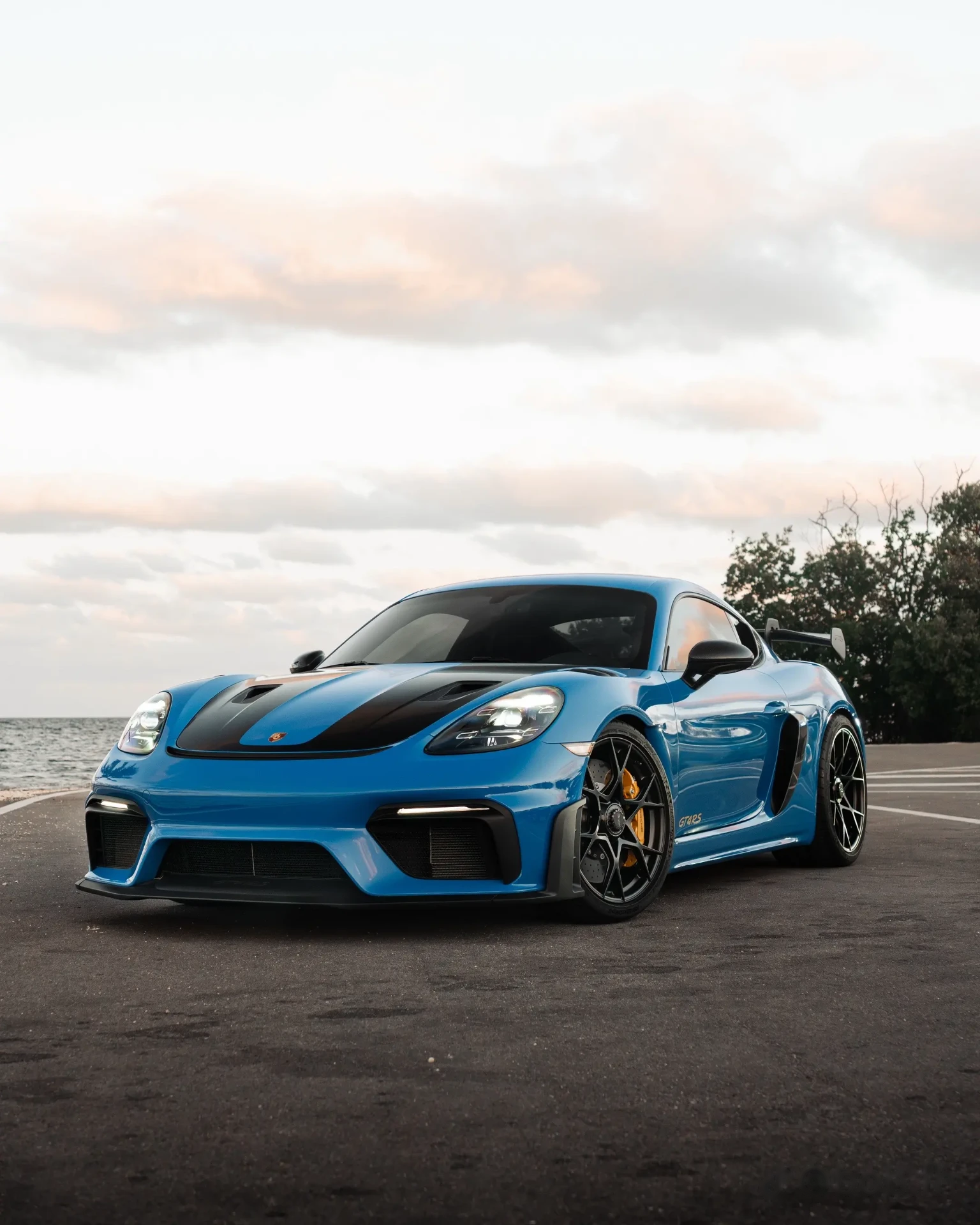 Blue Porsche GT4 RS front three-quarter by the ocean